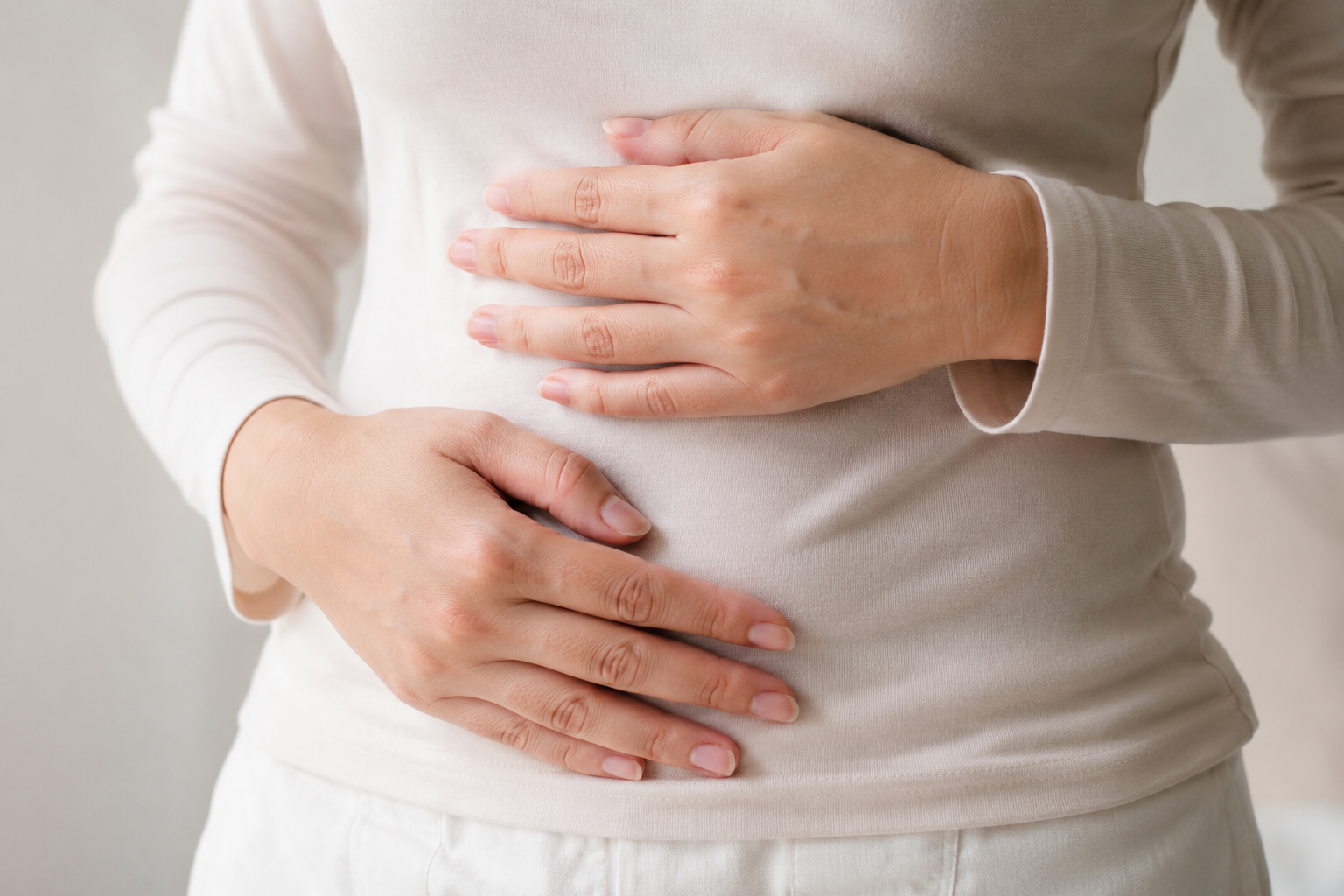 Close-up of a woman's hands on her stomach, representing gut and digestive health
